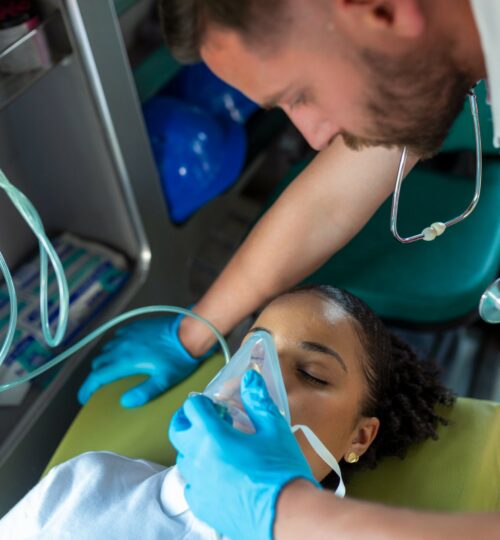paramedic-healthcare-emergency-staff-taking-care-lying-down-young-woman-patient-stretcher-with-medical-ventilator-system-bagvalve-masks-inside-medical-service-ambulance-car-scaled-1.jpg